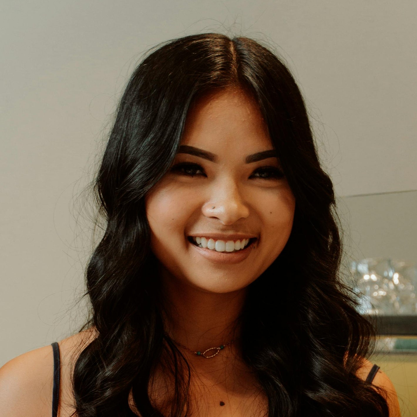 Woman in a black dress using a tablet at a counter with a smiling expression.